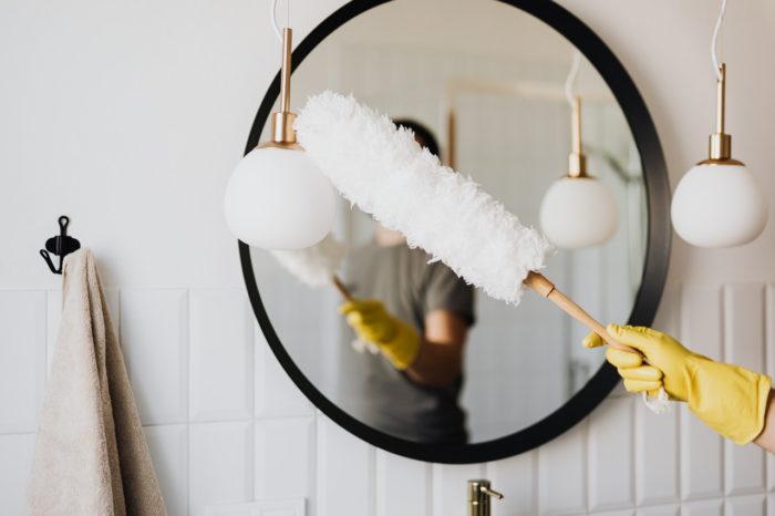 woman dusting mirror to symbolize payroll & hr spring cleaning tips for your business